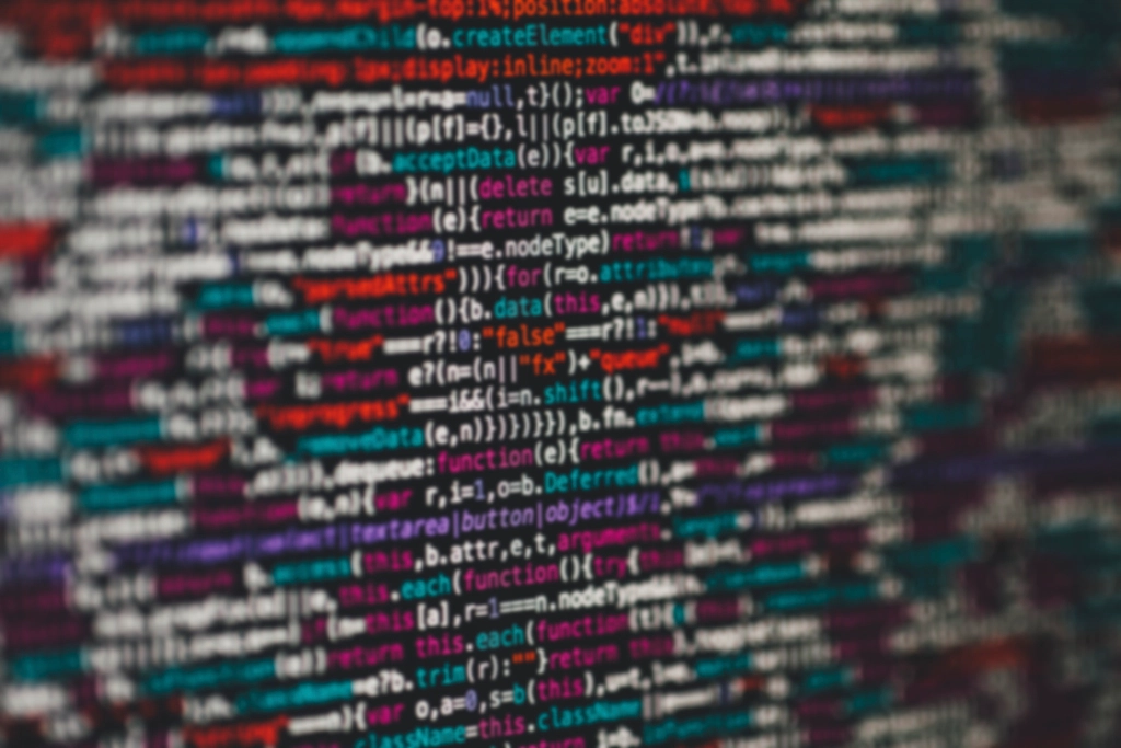 A slightly blurred close-up of colourful JavaScript code on a dark screen.